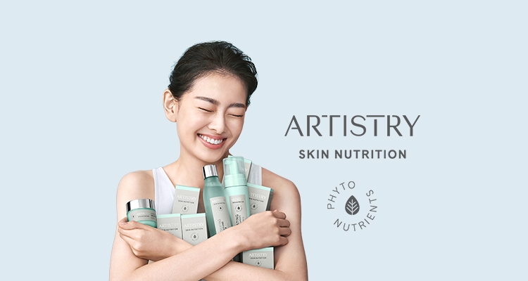 Happy Asian woman holding several ARTISTRY SKIN NUTRITION products to her chest 
