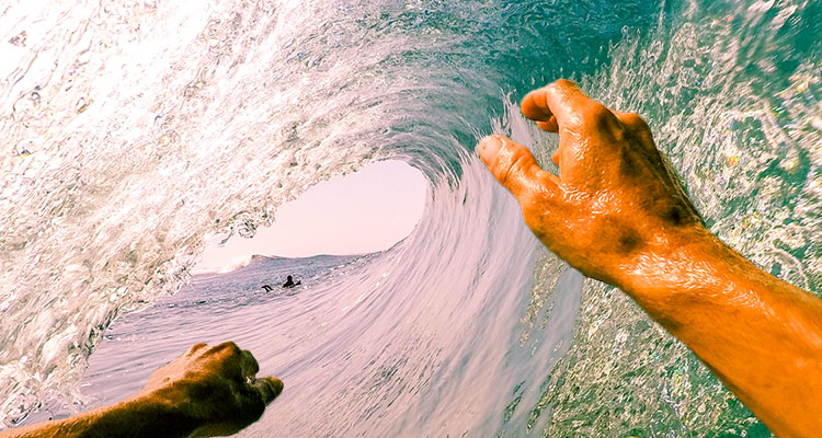 Perspective shot of a person surfing through a tunnel wave 
